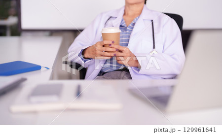 Asian Adult Female Doctor Takes Coffee Break in Modern Office Professional Healthcare Worker Relaxing During Busy Work Day Asian Adult Female Doctor Takes Coffee Break in Modern Office Professional Healthcare Worker Relaxing During Busy Work Day 129961641