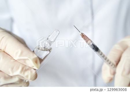 close up of healthcare professional preparing syringe with medication close up of healthcare professional preparing syringe with medication 129963008
