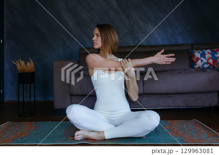 woman doing yoga at home stretching arm 129963081