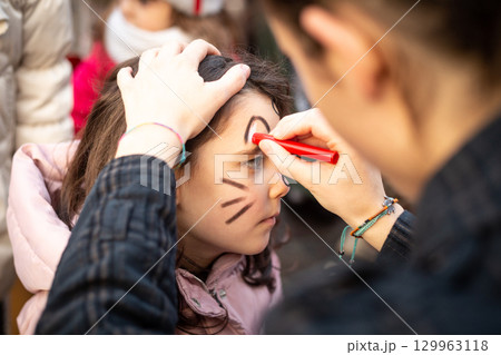 side view of a child face painting at carnival 129963118