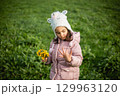 small girl with bouquet of dandelions in hand calculating the fingers on other hand 129963120