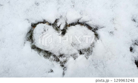 Heart, the love sign, on a snow covered in the winter time. Romantic background. 129963248