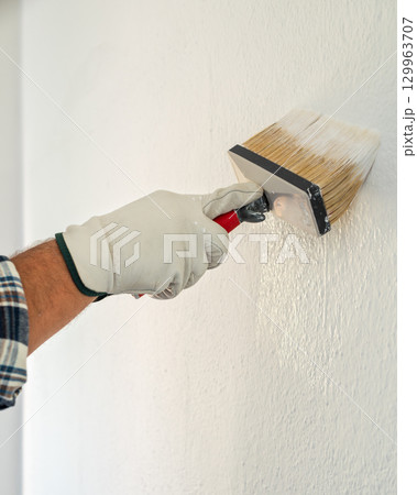 House painter worker painting a wall white. Building. House painter worker painting a wall white. Building. 129963707
