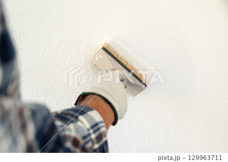 House painter worker painting a wall white. Building. 129963711