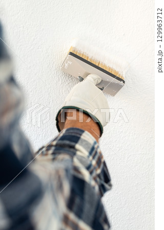 House painter worker painting a wall white. Building. House painter worker painting a wall white. Building. 129963712