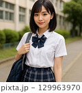スクールバックを持ち、制服を着た微笑む女子高生 129963970