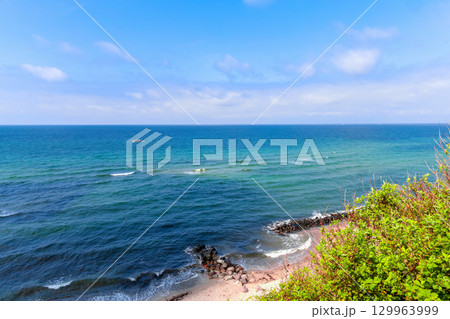 Tranquil beach scene with rock and blue sky with clouds Tranquil beach scene with rock and blue sky with clouds 129963999