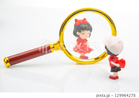 Miniature figures exploring a world magnified through a large lens in soft lighting 129964278