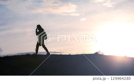 Hiker enjoying a peaceful sunset stroll along a scenic trail in nature 129964280