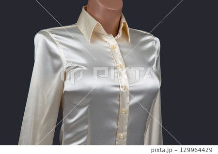 Elegant silk blouse with buttons displayed on a mannequin against a dark background Elegant silk blouse with buttons displayed on a mannequin against a dark background 129964429
