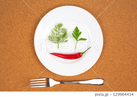 Chili pepper, cilantro, and dill arranged creatively on a white plate for artistic presentation Chili pepper, cilantro, and dill arranged creatively on a white plate for artistic presentation 129964434