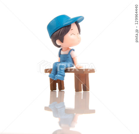 Miniature person sits happily on a wooden bench in a bright, serene environment Miniature person sits happily on a wooden bench in a bright, serene environment 129964440