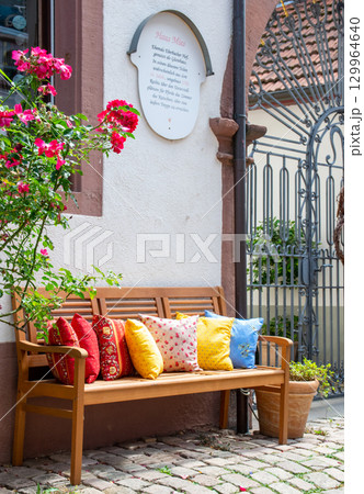 Wood romantic bench with a lot of multicolor pillows outdoor near stone house and rose. Wood romantic bench with a lot of multicolor pillows outdoor near stone house and rose. 129964640