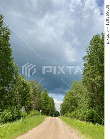 A Serene and Peaceful Dirt Road Meandering Through Dramatic, Beautifully Cloudy Skies 129965638