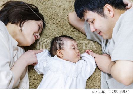両親と一緒に寝転ぶ赤ちゃん 129965984
