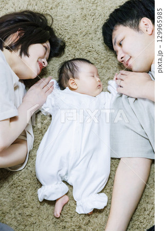 両親と一緒に寝転ぶ赤ちゃん 129965985