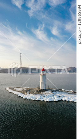 Aerial view of the lighthouse in winter in the ice at dawn 129965994