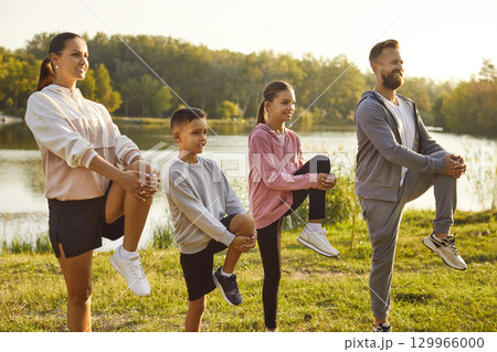 Fit and active happy parents with two kids boy and girl doing sport exercises in nature. 129966000