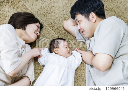 両親と一緒に寝転ぶ赤ちゃん 129966043