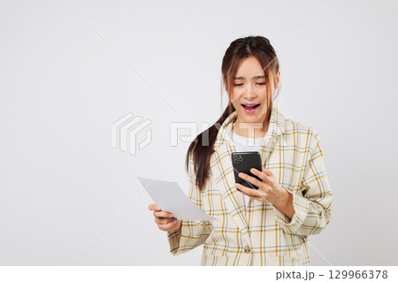 Worried woman looks at phone and invoice, trying to solve financial issues and financial stress over bill payments. isolated studio white background Worried woman looks at phone and invoice, trying to solve financial issues and financial stress over bill payments. isolated studio white background 129966378