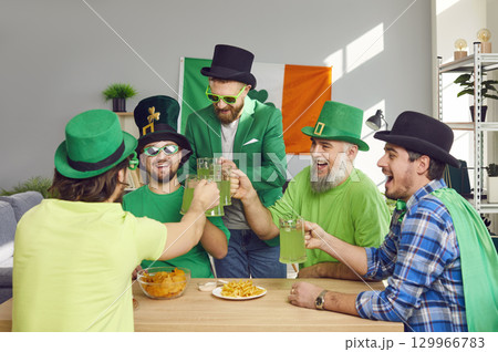 Happy male friends in costumes drinking green beer and having fun at Patrick's Day party Happy male friends in costumes drinking green beer and having fun at Patrick's Day party 129966783