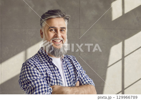 Portrait of happy smiling handsome bearded mature man in casual shirt with crossed arms Portrait of happy smiling handsome bearded mature man in casual shirt with crossed arms 129966789