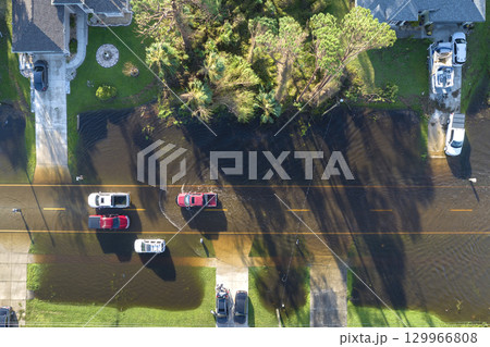 Flooded Florida road with evacuating cars and surrounded with water houses in suburban residential area. Consequences of hurricane natural disaster 129966808