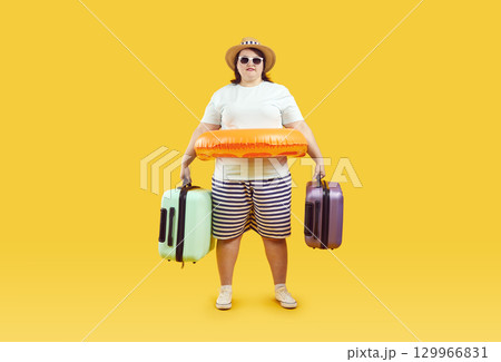 Excited plus size standing with suitcases and inflatable ring going on vacation Excited plus size standing with suitcases and inflatable ring going on vacation 129966831