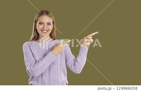 Portrait of blonde young woman pointing with her fingers to side Portrait of blonde young woman pointing with her fingers to side 129966838