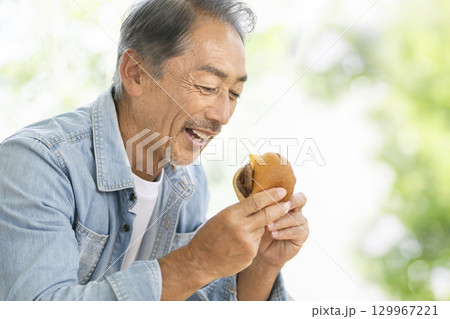 ハンバーガーを食べるシニア男性 129967221