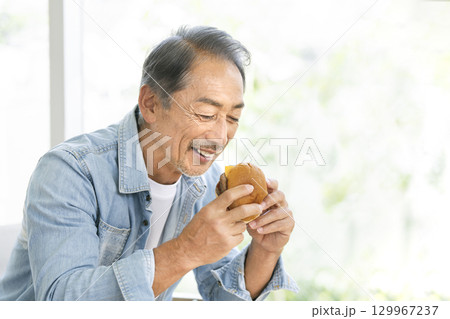 ハンバーガーを食べるシニア男性 129967237