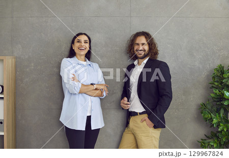 Team of two happy business people, colleagues and friends standing by office wall 129967824