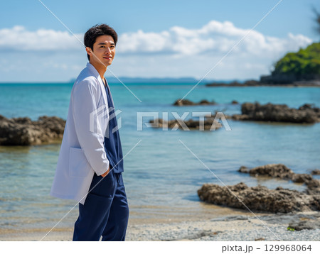 離島の海辺に立つ研修医 129968064