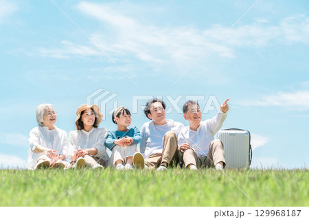 青空の見える公園・丘に座る家族・親子・三世代家族（父親・母親・娘・祖母・祖父） 129968187