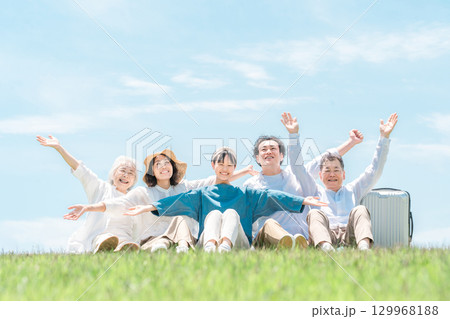 青空の見える公園・丘に座る家族・親子・三世代家族（父親・母親・娘・祖母・祖父） 129968188