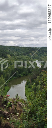 Idyllic River Bend Through Verdant Forest Under Cloudy Sky, Perfect for Outdoor Adventures 129968247