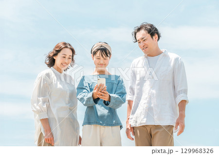 青空の下にいる3人の親子(家族旅行,ファミリー,父親,母親,娘) 青空の下にいる3人の親子(家族旅行,ファミリー,父親,母親,娘) 129968326