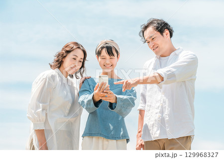 青空の下にいる3人の親子（家族旅行,ファミリー,父親,母親,娘） 129968327