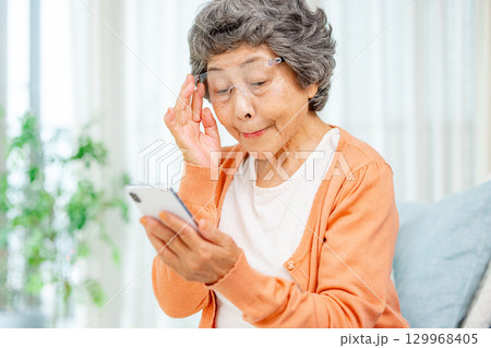 スマートフォンの画面を見るシニア女性 129968405