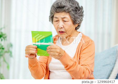通帳を持つシニア女性　悩む 129968417