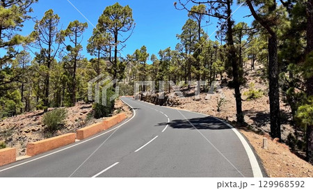 Discover the stunning beauty of a winding road through lush green forests, an ideal getaway 129968592