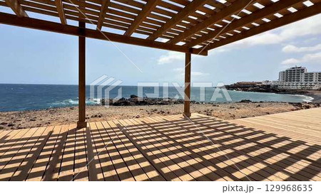 Experience a breathtaking scenic coastal view while relaxing under a charming wooden pergola 129968635
