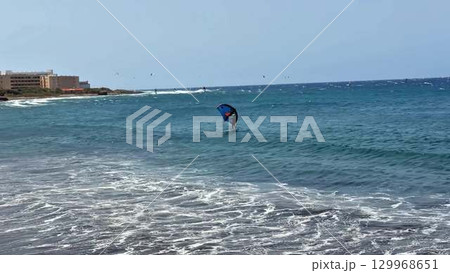Experience the thrilling excitement of a kite surfer gliding over the magnificent waves now Experience the thrilling excitement of a kite surfer gliding over the magnificent waves now 129968651