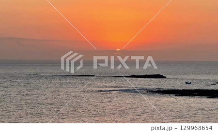 A Serene Sunset Over the Ocean with Silhouetted Rocks that Creates a Stunning Visual Scene A Serene Sunset Over the Ocean with Silhouetted Rocks that Creates a Stunning Visual Scene 129968654