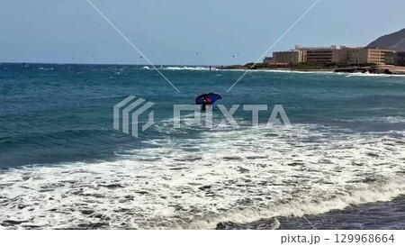 An Adventurer Reveling in Exciting Watersports While Holding a Colorful Umbrella Amidst Ocean Waves An Adventurer Reveling in Exciting Watersports While Holding a Colorful Umbrella Amidst Ocean Waves 129968664