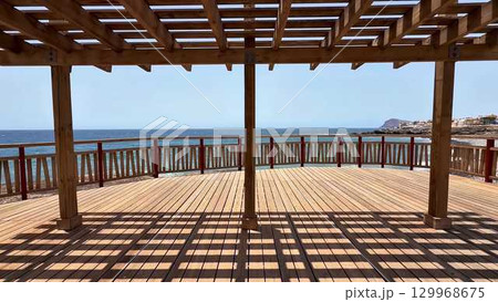 Enjoy a scenic ocean view from a lovely wooden deck with a stylish pergola, perfect for relaxation 129968675