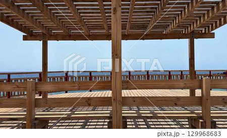 A beautifully crafted wooden pergola that overlooks the stunning ocean and coastal landscape 129968683