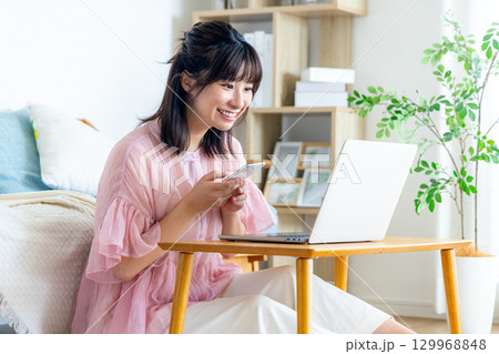 リビングでスマホを使う若い女性 129968848