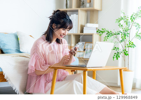 リビングでスマホを使う若い女性 129968849
