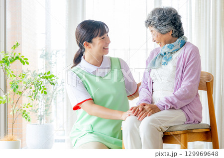 椅子に座る介護士の女性と若い介護職員 椅子に座る介護士の女性と若い介護職員 129969648
